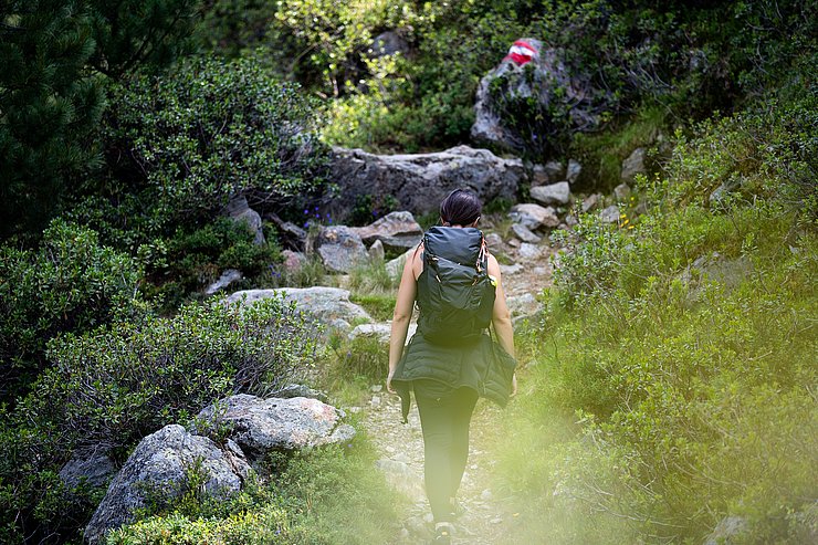© Marco Christanell Eine Frau auf einem Wanderweg vor einer rot-weiß-roten Markierung