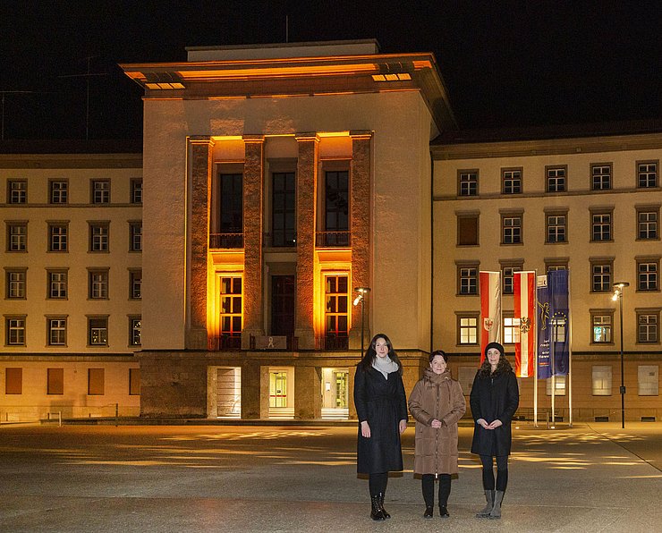 © Tiroler Landtag/Die Fotografen LTPin Sonja Ledl-Rossmann (Mitte), VPin Sophia Kircher und LRin Eva Pawlata vor dem orange beleuchteten Landhaus 1