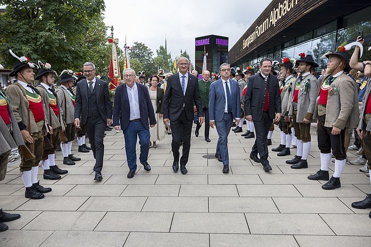 Personen schreiten entlang, flankiert von Schützen
