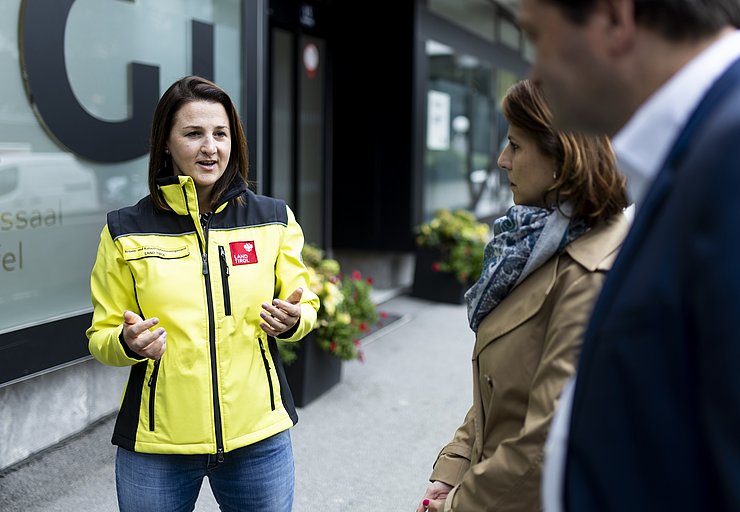 Landesrätin Astrid Mair mit gelber Einsatzjacke im Gespräch mit 2 Personen