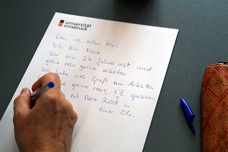 Hand mit Kuli und beschriebenem Blatt