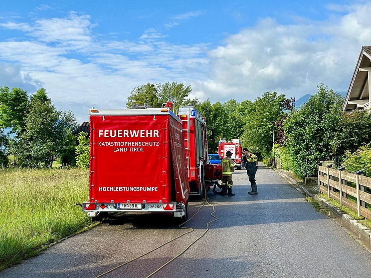 Feuerwehrautos stehen auf einer überschwemmten Straße.