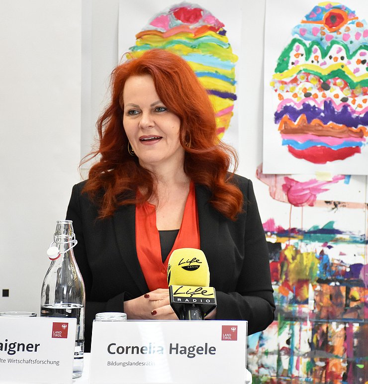 © Land Tirol/Hörmann Foto von einer Frau vor einer bunt bemalten Wand, während sie spricht