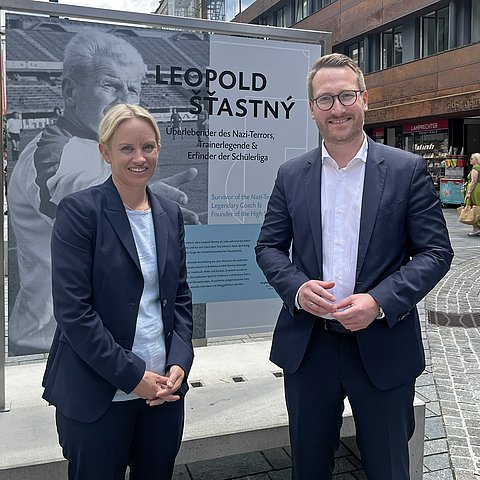 zwei Personen vor Plakat