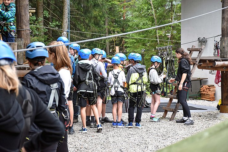 Eine Menge an Kindern werden im Klettergarten eingewiesen.