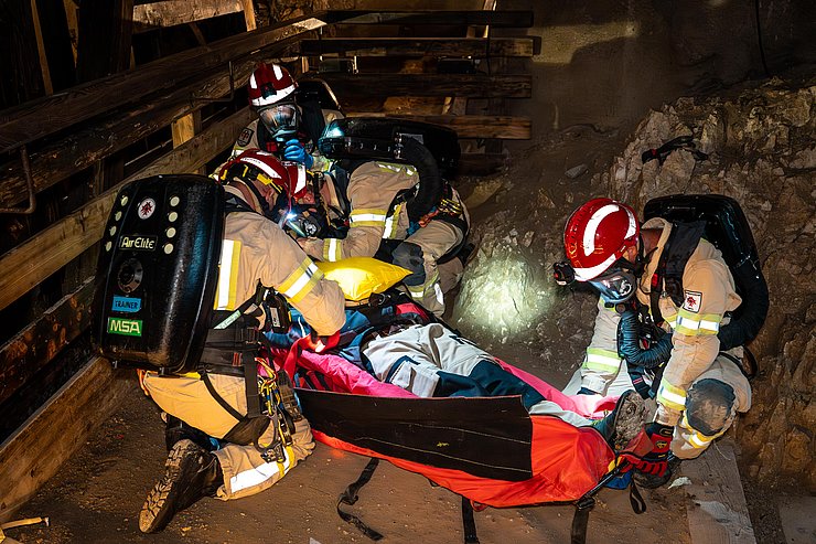 Grubenretter mit Atemschutzmasken heben Patienten in Tragetuch