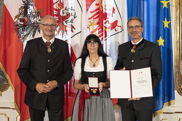 © Land Tirol/Die Fotografen links LH Mattle, in der Mitte Frau Laner und rechts LH Kompatscher, halten Medaille und Verdiensturkunde