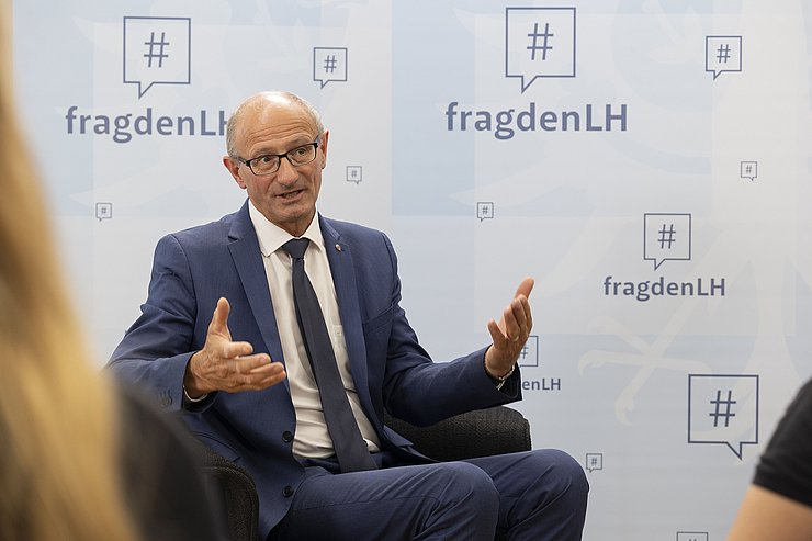 © Land Tirol/Die Fotografen LH Anton Mattle sitzt auf einem Stuhl und beantwortet die Fragen der Schülerinnen.