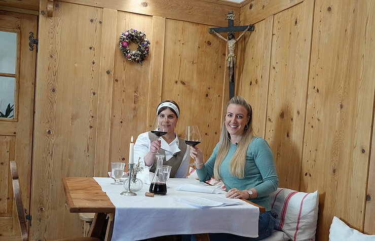 © Euregio Sitzen auf Ecktisch in hölzerner Stube, heben Weinglas