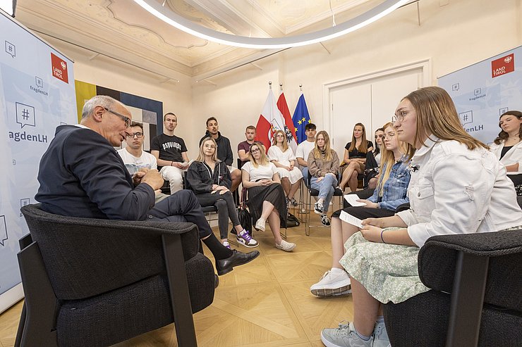 © Land Tirol/Die Fotografen Landeshauptmann spricht zu den Schülerinnen und Schülern die im Halbkreis sitzen