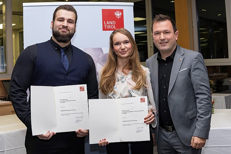 © Land Tirol/Die Fotografen Die bestausgezeichneten Lehrlinge Mehmetaj Arlind (Speditionskaufmann im dritten Lehrjahr bei Gebrüder Weiss GmbH) und Kimberly Klammer (Einzelhandel/Einrichtungsberaterin im dritten Lehrjahr bei XXXLutz KG) mit Landtagsabgeordneten Andreas Kirchmair.
