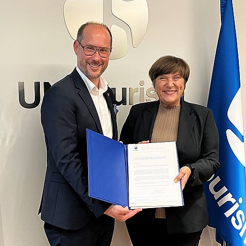 zwei Personen mit Urkunde in der Hand