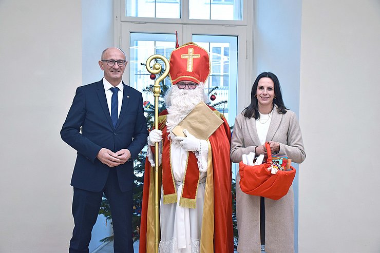 © Land Tirol/Hörmann LH Anton Mattle, der Nikolaus und GFin von "Bruder und Schwester in Not" Marika Eisner zusammen vor einem Christbaum.