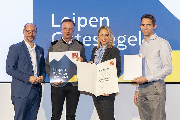 Vier Menschen sind bei einem Gruppenbild zu sehen.