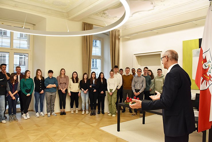Die Lehrlinge stehen nebeneinander in einer Reihe im Büro des Landeshauptmanns und der Landeshauptmann spricht zu ihnen.
