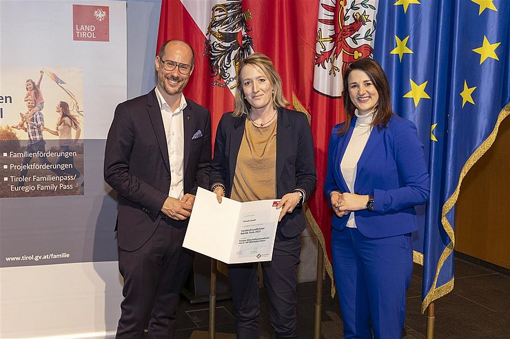 drei Personen mit Urkunde