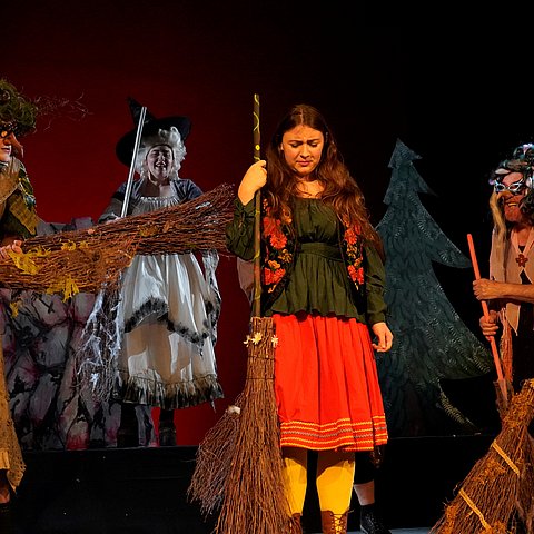 Als Hexen verkleidete Menschen stehen auf einer Bühne.