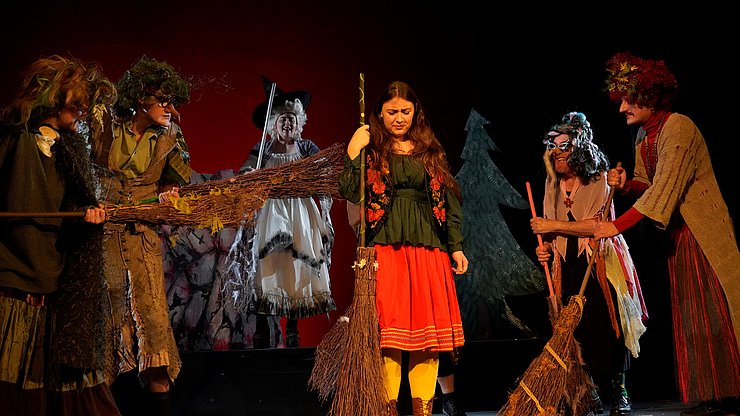 Als Hexen verkleidete Menschen stehen auf einer Bühne.