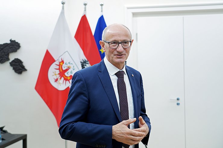 © Land Tirol/Neuner Landeshauptmann Mattle steht vor Fahnen.