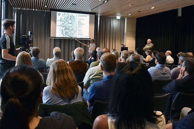 © Land Tirol/Baumegger Aufnahme aus dem Pfarrsaal: Menschen auf Stühlen sitzend verfolgen Vortrag; im Hintergrund zeigt Vortragender mit Stock auf einer Leinwand auf eine Karte von Ebbs