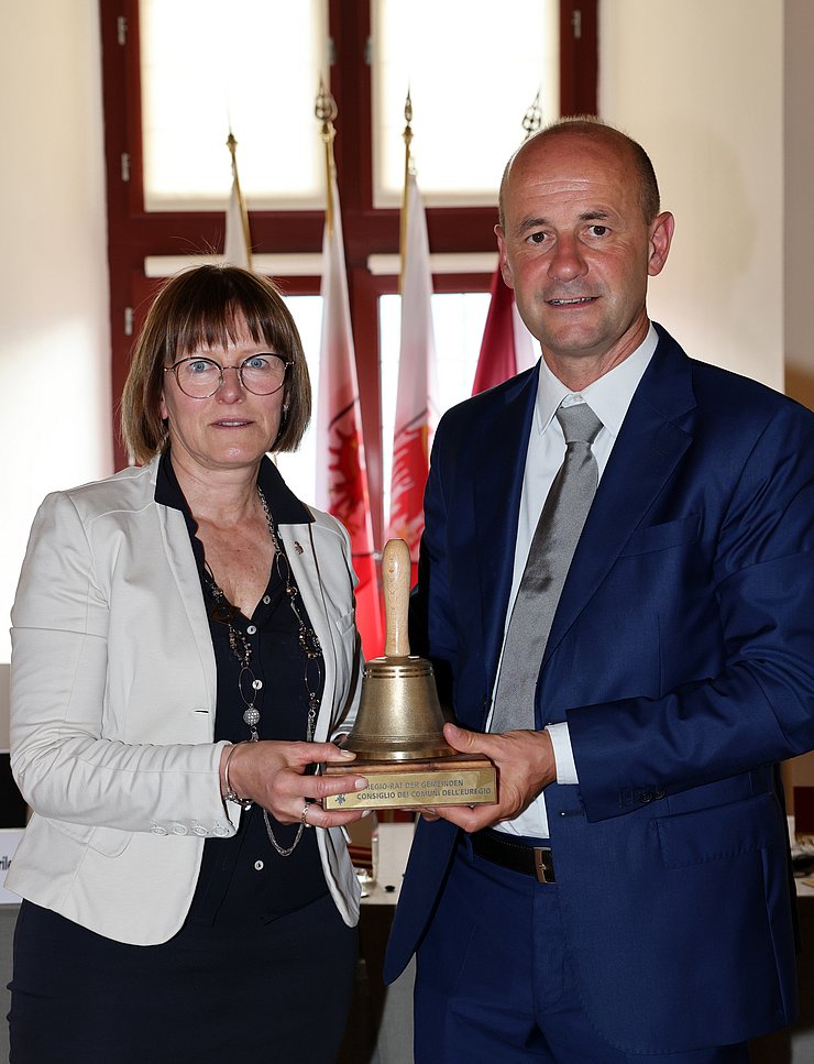 © Euregio/Matteo Rensi Gianmoena und Noletti halten die Glocke des Euregio-Rates der Gemeinden