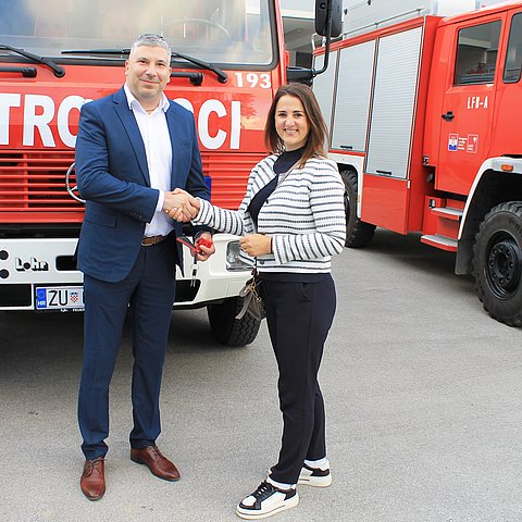 Mair und Mann vor Auto stehend Hand schüttelnd 