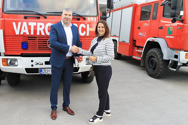 © Land Tirol Mair und Mann vor Auto stehend Hand schüttelnd