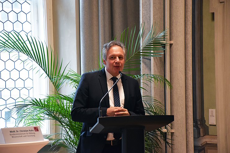 Mann steht vor Rednerpult und spricht