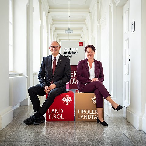 LH Mattle und LTPin Ledl-Rossmann sitzen in einem Gang nebeneinander auf Würfeln.