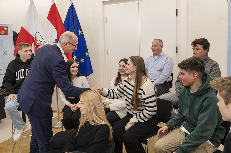 © Land Tirol/Die Fotografen Der Landeshauptmann grüßt händeschüttelnd eine Schülerin.