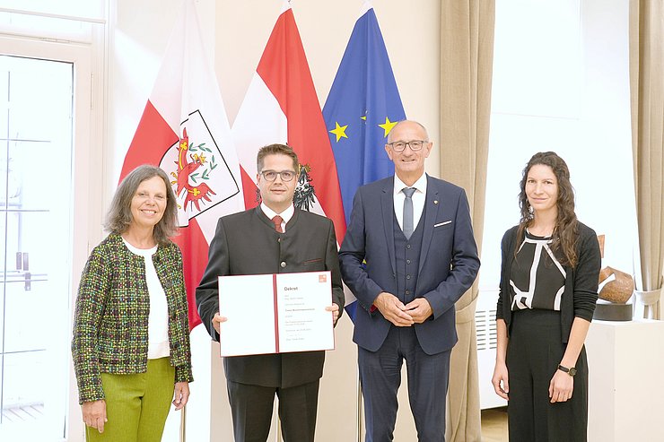 © Land Tirol/Dominik Personen stehen vor Fahnen, Walser hält Dekret