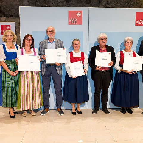 Bezirkshauptfrau Katharina Rumpf, Gemeindevorständin der Marktgemeinde Reutte Daniela Rief und LH Anton Mattle stehen gemeinsam mit den Geehrten der Gemeinde Reutte bei einem Gruppenfoto zusammen
