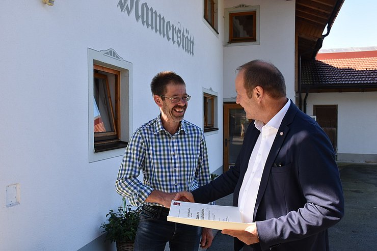 Josef Geisler schüttelt Alois Mauracher die Hand und überreicht im die Urkunde.