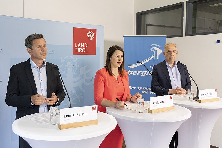 © Land Tirol/Die Fotografen Drei RednerInnen stehen an Stehtischen mit Mikrofonen