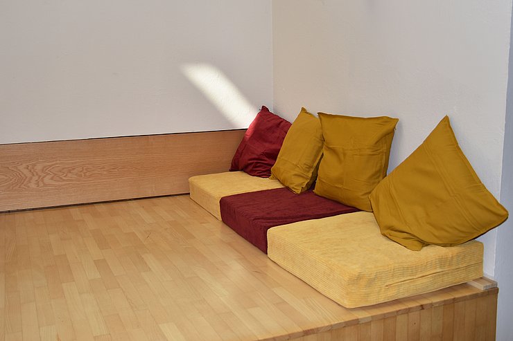 Nische mit Holzboden und Polstern (gelb, rot)