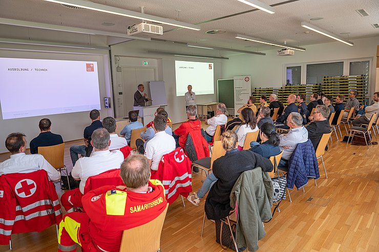 Personen auf Stühlen sitzend lauschen Vortrag 
