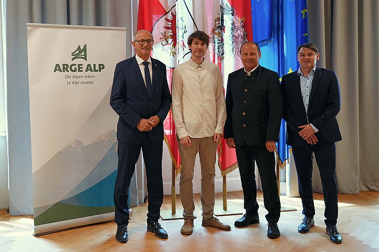 © Land Tirol/Dorfmann Personen stehen nebeneinander, vor Fahnen und ARGE-ALP-Rollup