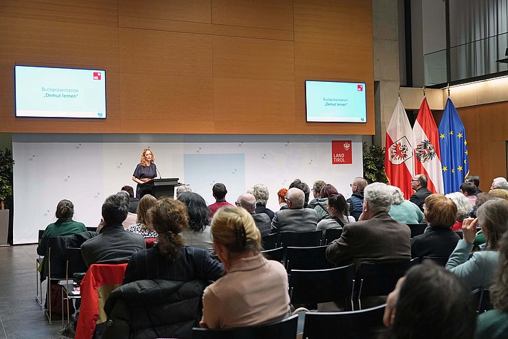 © Land Tirol/Dorfmann Raum mit Menschen - Bild über Köpfe hinweg auf Bühne