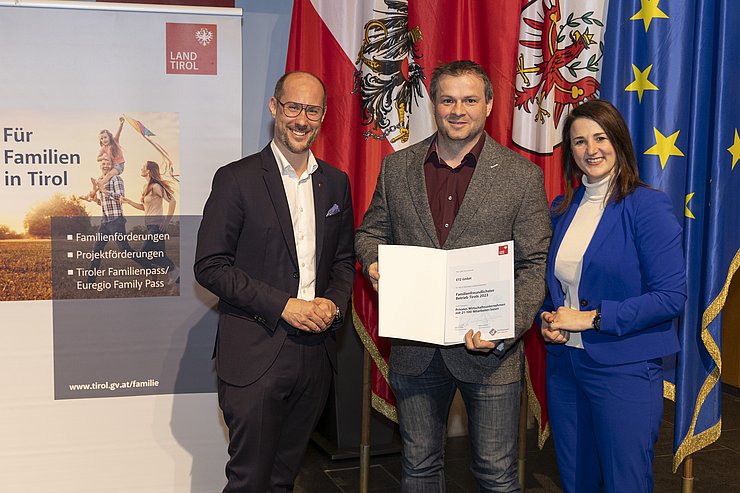 drei Personen mit Urkunde