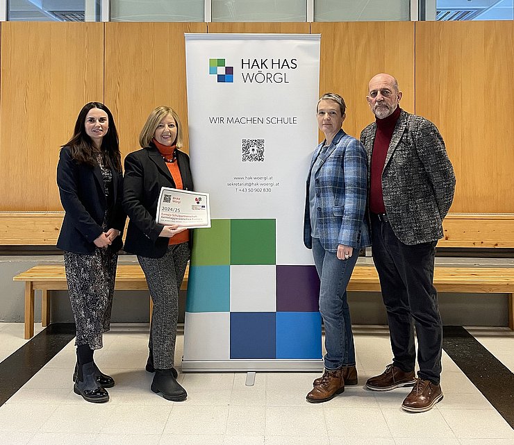 © Euregio Personen stehen mit Aufkleber vor Rollup der Schule