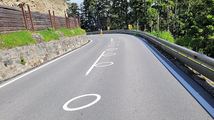 © Land Tirol Weiße Ellipsen auf Asphalt in einer engen Kurve