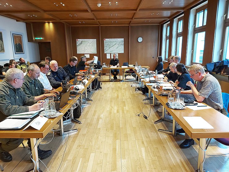 Raum mit U-förmiger Tischaufstellung an der Personen von Laptops sitzen 