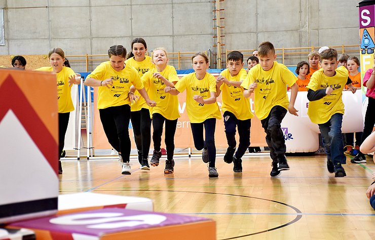 Mehrere Schülerinnen und Schüler laufen auf die gestapelten Würfel zu.