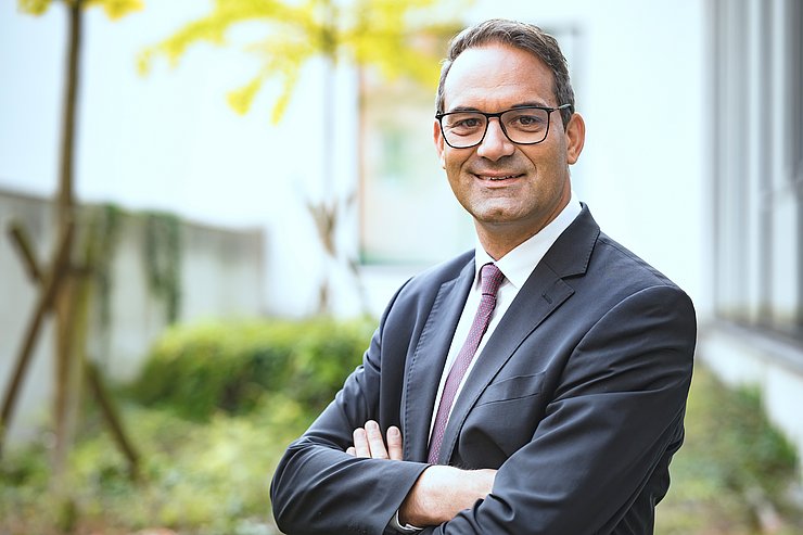 Christoph Walser mit verschränkten Armen vor verschwommenen Hintergrund