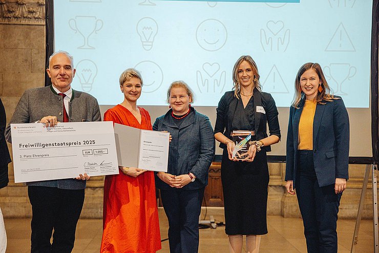 Fünf Menschen halten eine Auszeichnung in die Kamera.