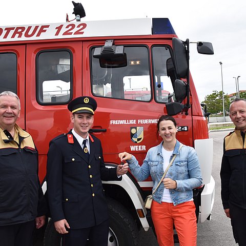 Alfons Gruber, Stipe Batur, Landesrätin Astrid Mair und Jakob Unterladstätter stehen vor dem Feuerwehrauto. Dabei übergibt die Landesrätin die Schlüssel an den Feuerwehrkommandanten Batur.