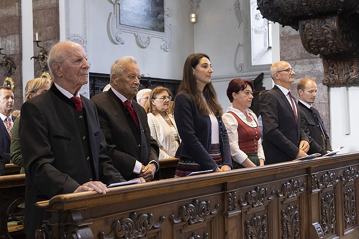 Personen stehen in Jesuitenkirchen bei Kirchenbank