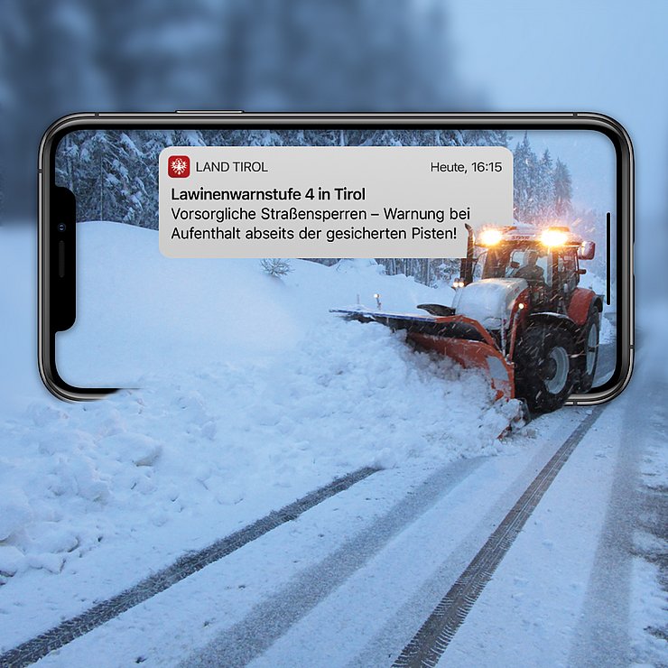 MockUp: Handy mit Push-Nachricht; aus Handy fährt ein Traktor, der gerade Schnee räumt
