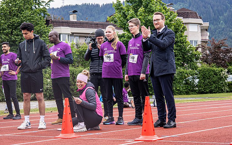 Wohlgemuth auf Sprintstrecke neben Personen in Sportgewand stehend