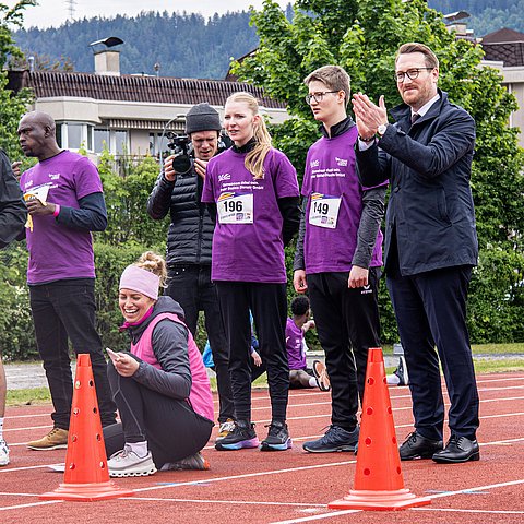 Wohlgemuth auf Sprintstrecke neben Personen in Sportgewand stehend